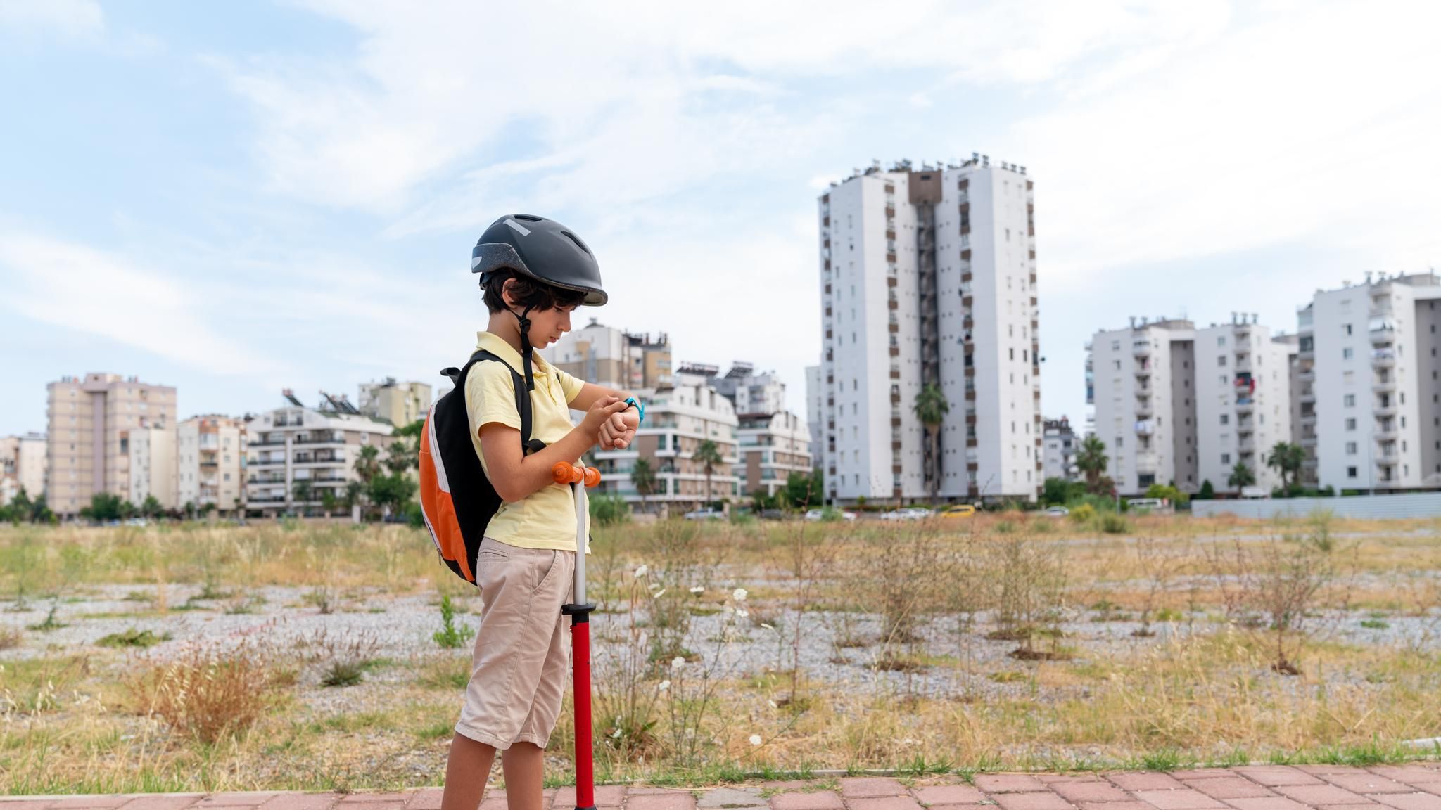 Kinder sind gern draußen unterwegs: Junge mit Roller auf dem Weg zur Schule
