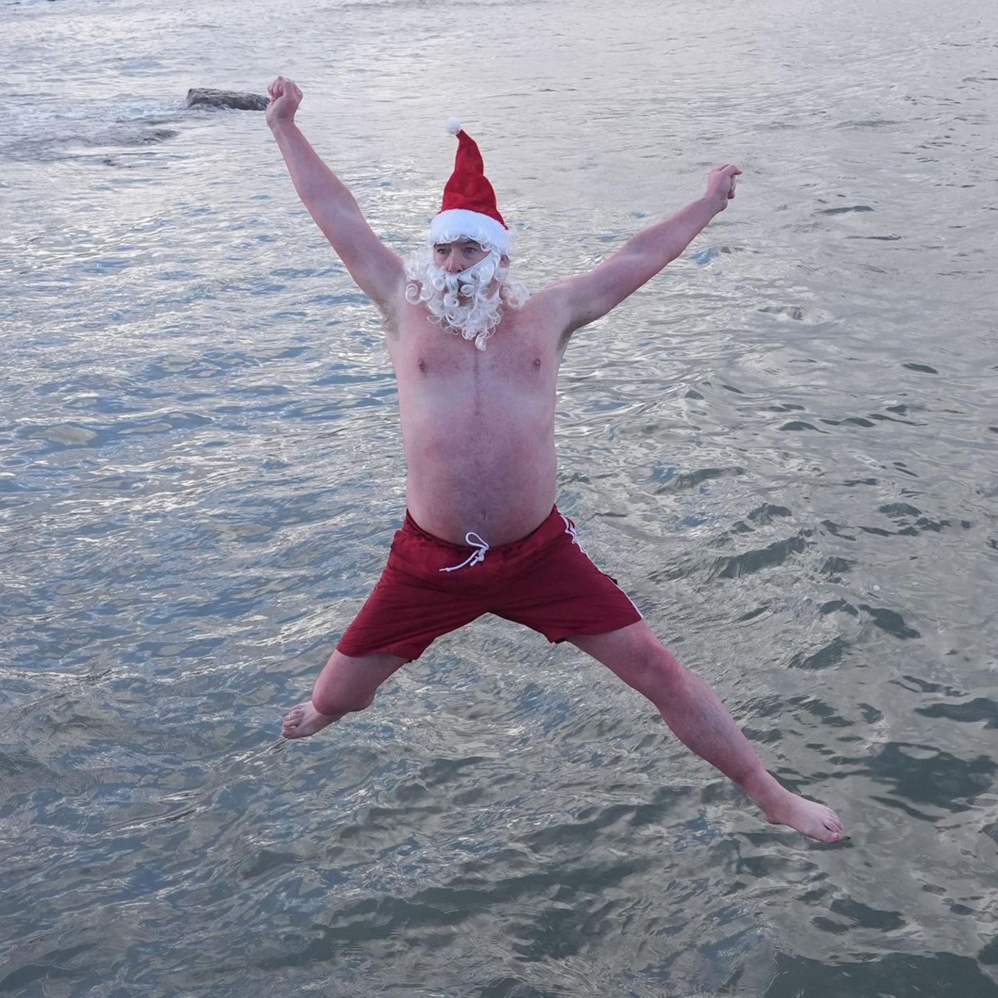Dublin, Irland. Mit Weihnachtsmütze und Santa-Bart springt ein Mann an der Badestelle Forty Foot in Sandycove ins Wasser. Das traditionelle Weihnachtsschwimmen findet hier jedes Jahr statt – und ist bei den winterlichen Temperaturen nichts für Frostbeulen