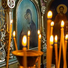 Glaube, Symbolbild: Kerzen in einer orthodoxen Kirche, im Hintergrund Ikonenbilder