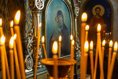 Glaube, Symbolbild: Kerzen in einer orthodoxen Kirche, im Hintergrund Ikonenbilder