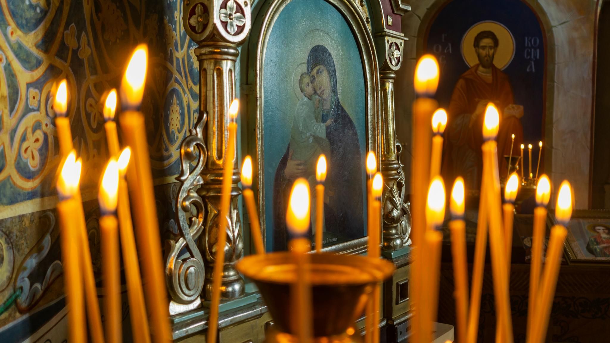 Glaube, Symbolbild: Kerzen in einer orthodoxen Kirche, im Hintergrund Ikonenbilder