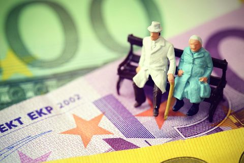 Seniorenpaar sitzt auf Geldscheinen, Symbolfoto Rente