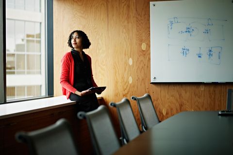 Eine Frau steht nachdenklich in einem Besprechungsraum