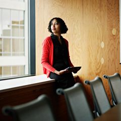 Eine Frau steht nachdenklich in einem Besprechungsraum