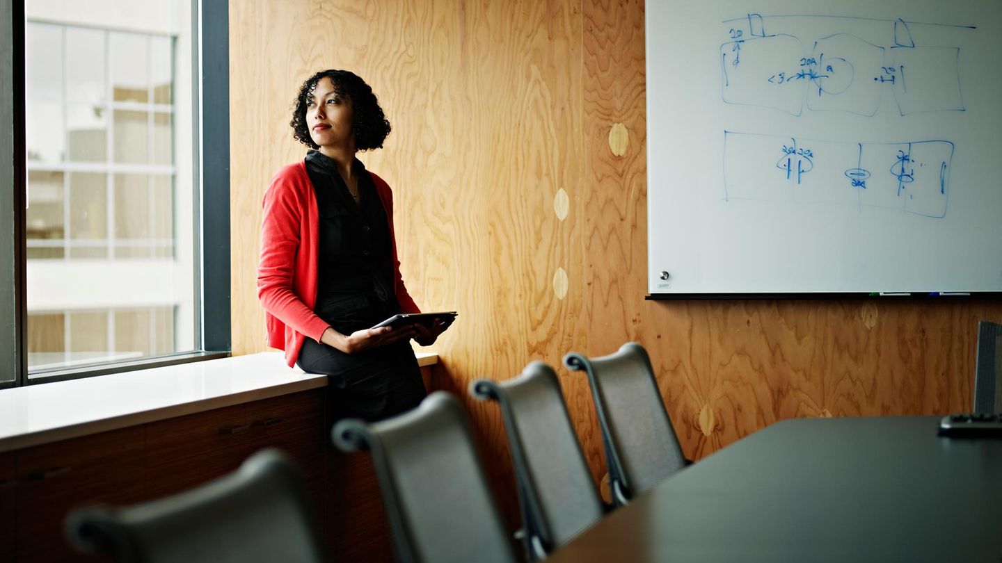 Eine Frau steht nachdenklich in einem Besprechungsraum