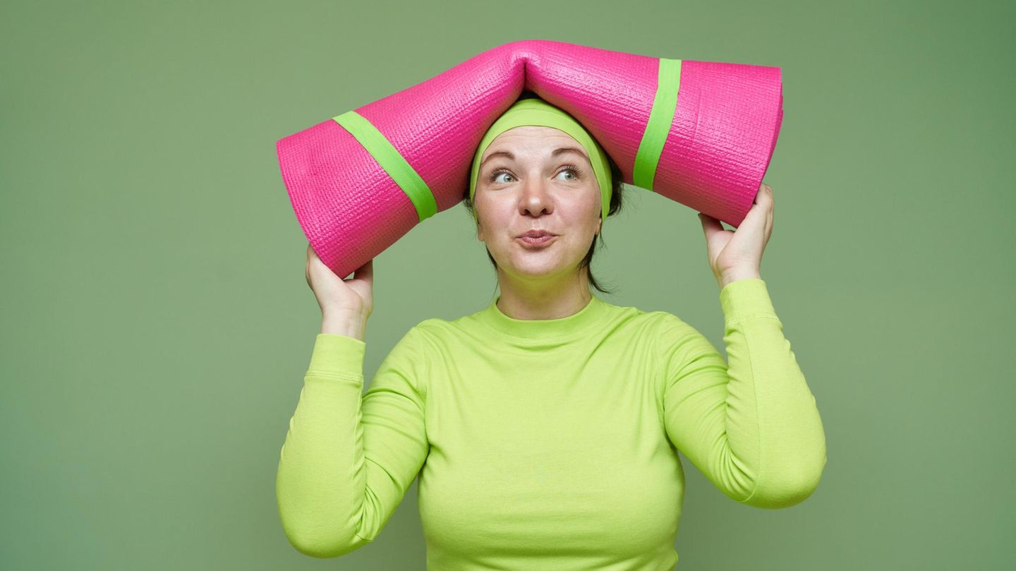 Gesund leben: eine Frau mit Yoga-Matte auf dem Kopf