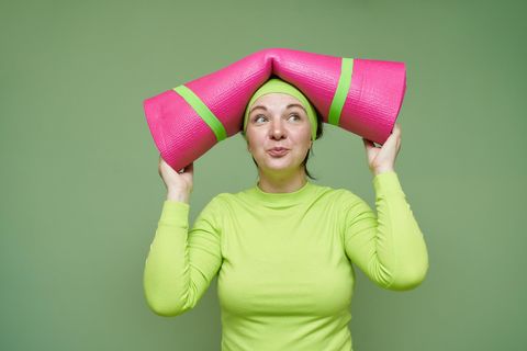 Gesund leben: eine Frau mit Yoga-Matte auf dem Kopf