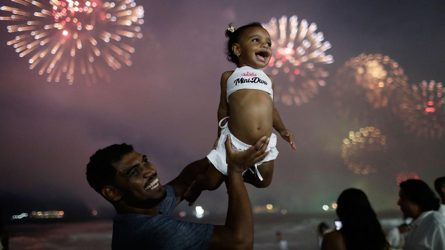 Ein Mann hebt seine Tochter während der Silvesterfeierlichkeiten am Copacabana-Strand