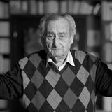 Walter Schultheiß schaut schaut aus einem Vorhang, den er mit beiden Händen offen hält