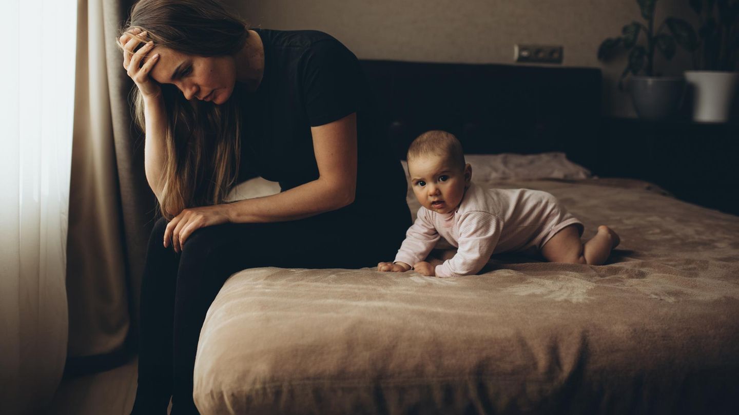 Eine Frau sitzt auf einem Bett neben ihrem Baby