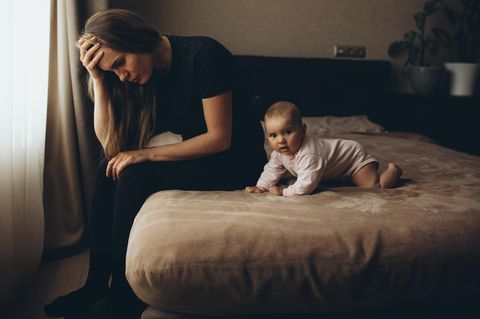 Eine Frau sitzt auf einem Bett neben ihrem Baby