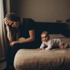 Eine Frau sitzt auf einem Bett neben ihrem Baby