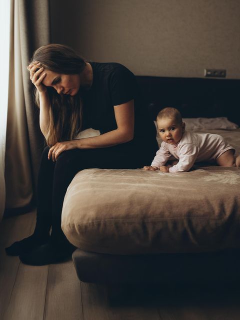 Eine Frau sitzt auf einem Bett neben ihrem Baby