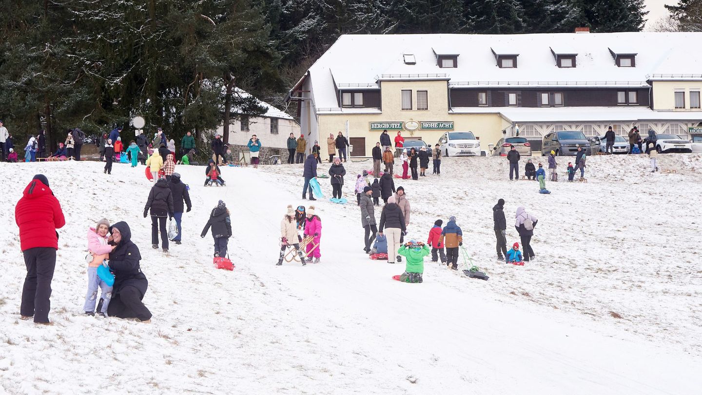 Familien fahren am Wochenende an einem Berghang an der Hohen Acht in der Eifel Schlitten - auch zum Wochenstart gibt es Schnee.