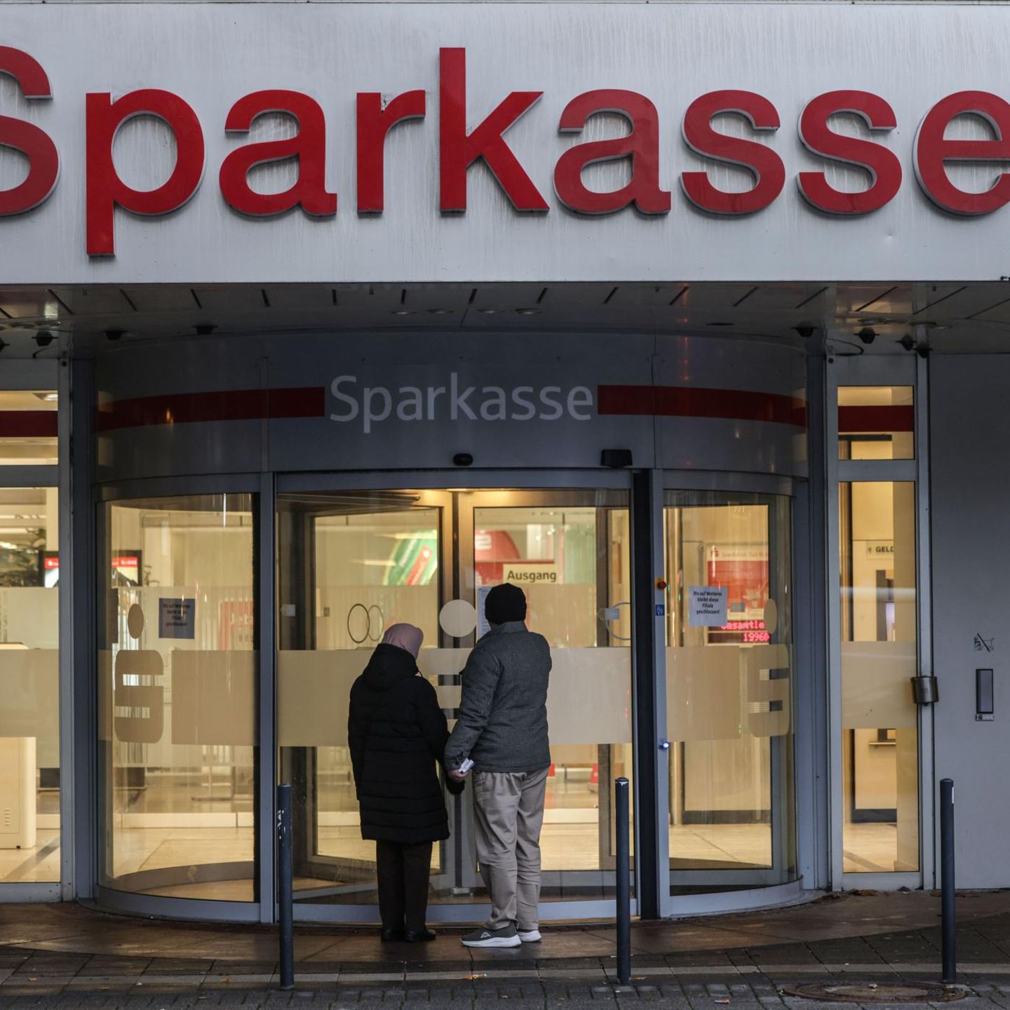 Zwei Menschen stehen vor der Sparkassen-Filiale in Gelsenkirchen, in die Unbekannte Ende Dezember eingebrochen sind