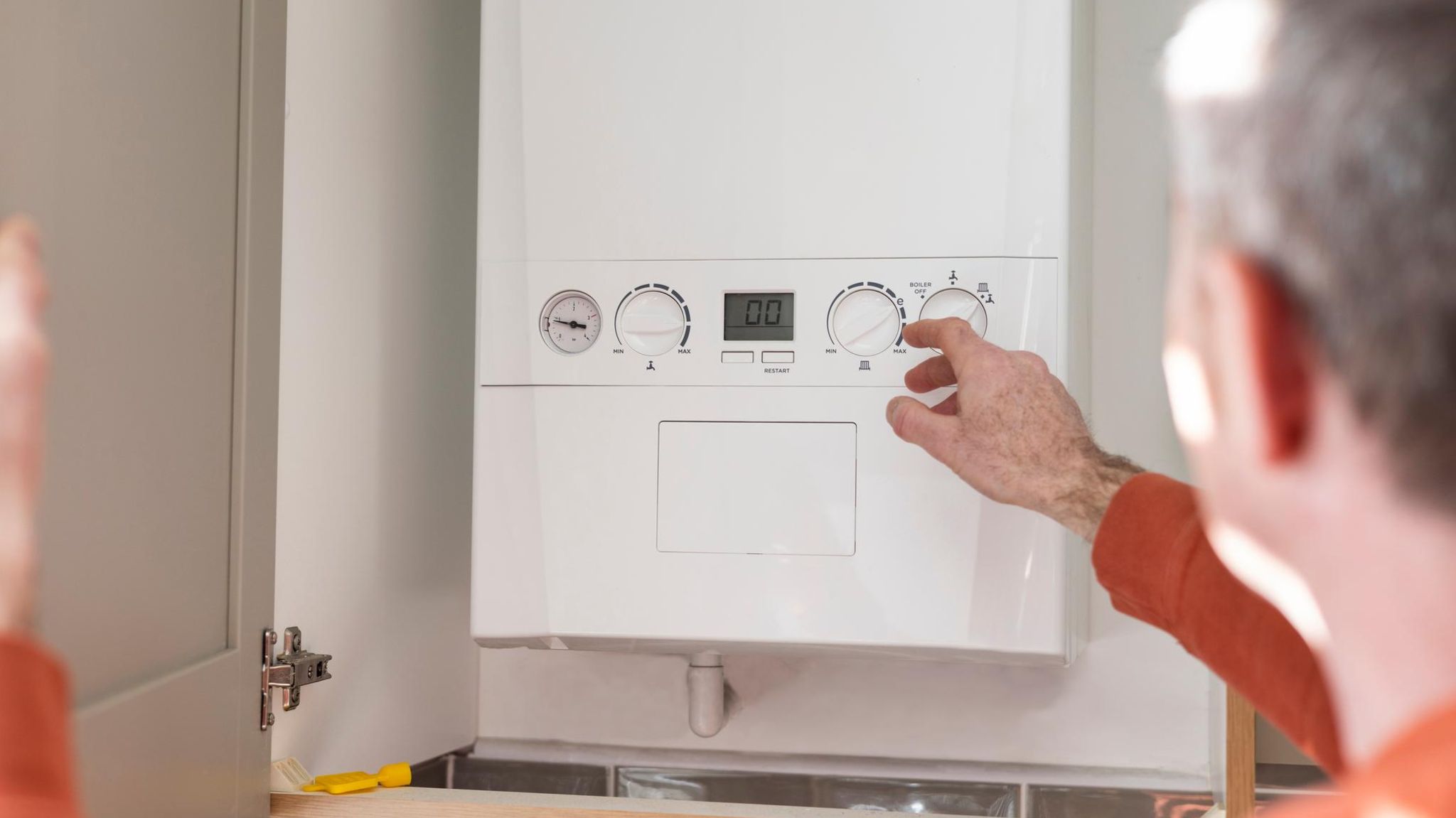 Günstige Gasanbieter: Ein Mann zeigt auf die Regler einer Gastherme
