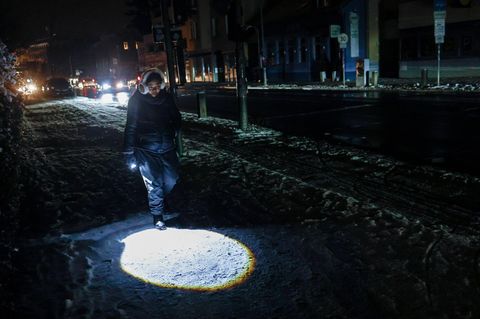 Eine Teenagerin geht mit Taschenlampe über die ansonsten dunkle Straße in Berlin während des Stromausfalls