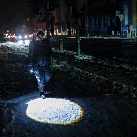 Eine Teenagerin geht mit Taschenlampe über die ansonsten dunkle Straße in Berlin während des Stromausfalls