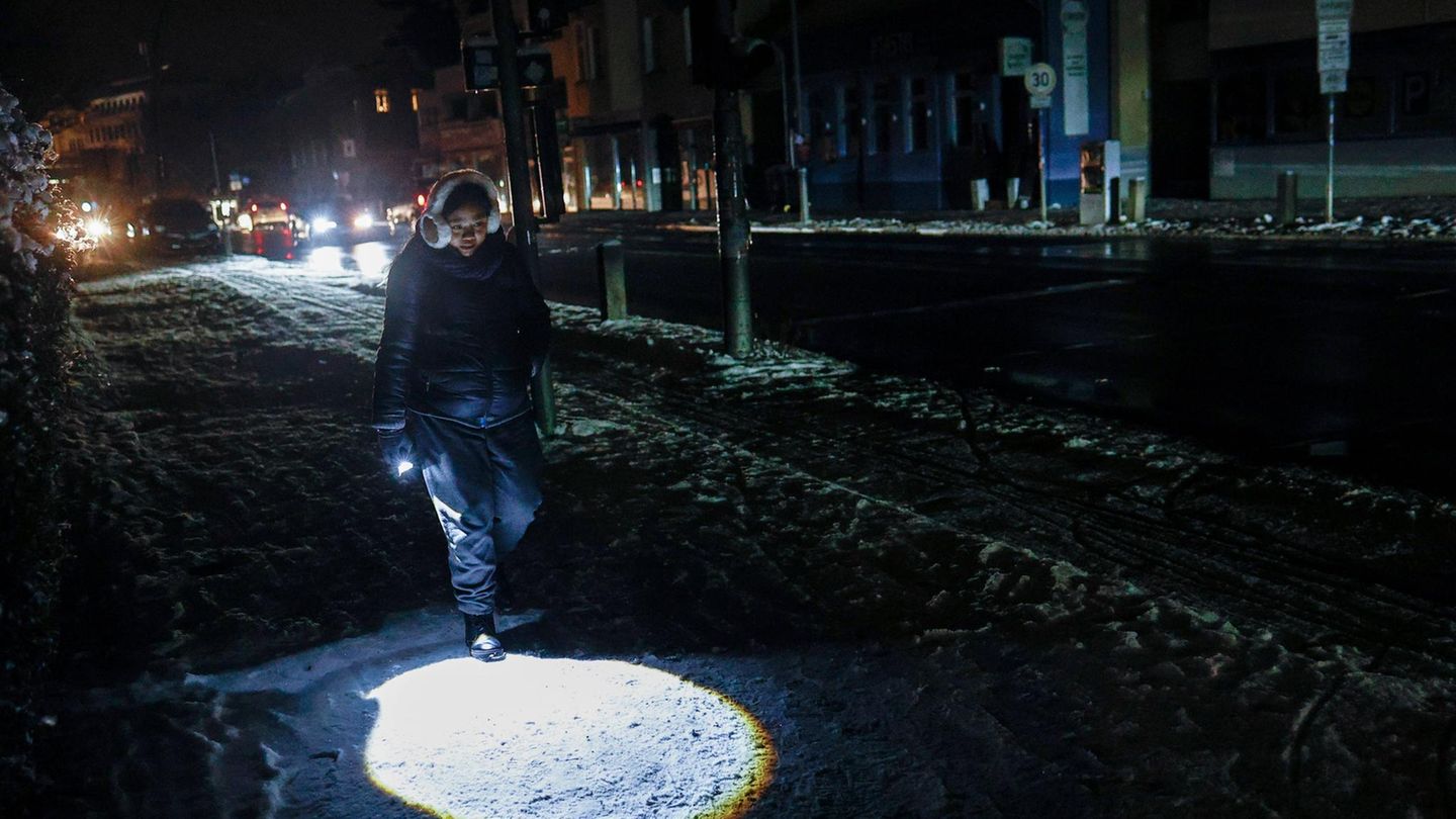 Eine Teenagerin geht mit Taschenlampe über die ansonsten dunkle Straße in Berlin während des Stromausfalls