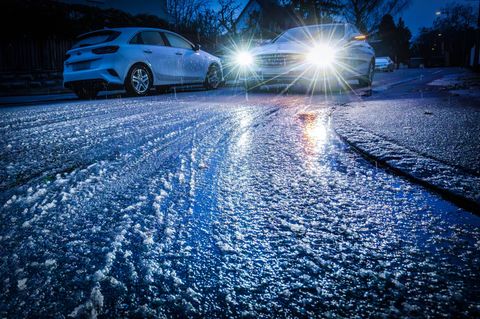 Winterliches Wetter: Ein Auto rollt über eine von Schnee und Frost überzogene Straße