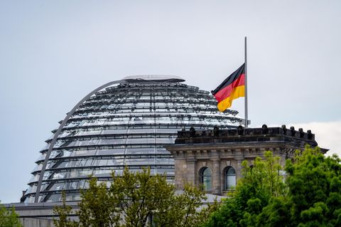 Eine Flagge weht auf Halbmast auf dem Reichstaggebäude vor der Reichstagskuppel