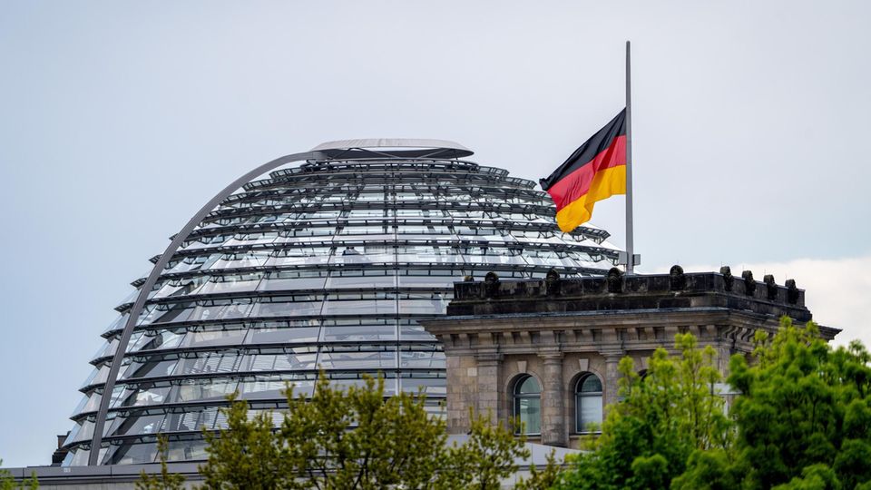 Eine Flagge weht auf Halbmast auf dem Reichstaggebäude vor der Reichstagskuppel