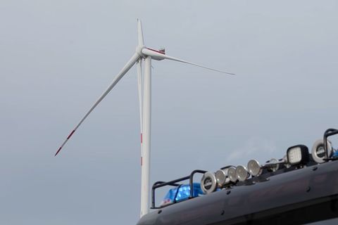 Ein Fahrzeug der Feuerwehr steht vor einem Windrad, bei dem ein Flügel beschädigt ist