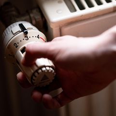 Eine rechte Hand dreht ein Heizungsventil auf 3 – Symbolbild Gasspeicher