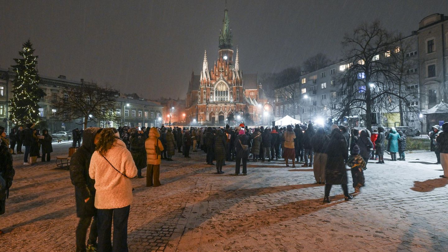 Singen wärmt auf! An einem kalten und verschneiten Abend versammeln sich Menschen auf dem Marktplatz vor der historischen Josefskirche in Krakau, um gemeinsam Lieder zu singen