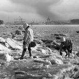 Schneekatastrophe zwei Männer mit Motorradhelmen auf Eisschollen