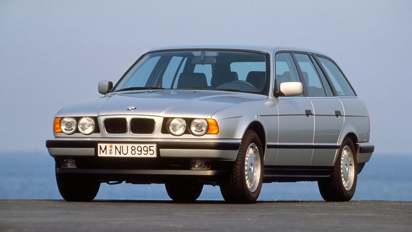 Ein silberner BMW 540i, E34 steht auf Asphalt, dahinter lila-blauer Himmel