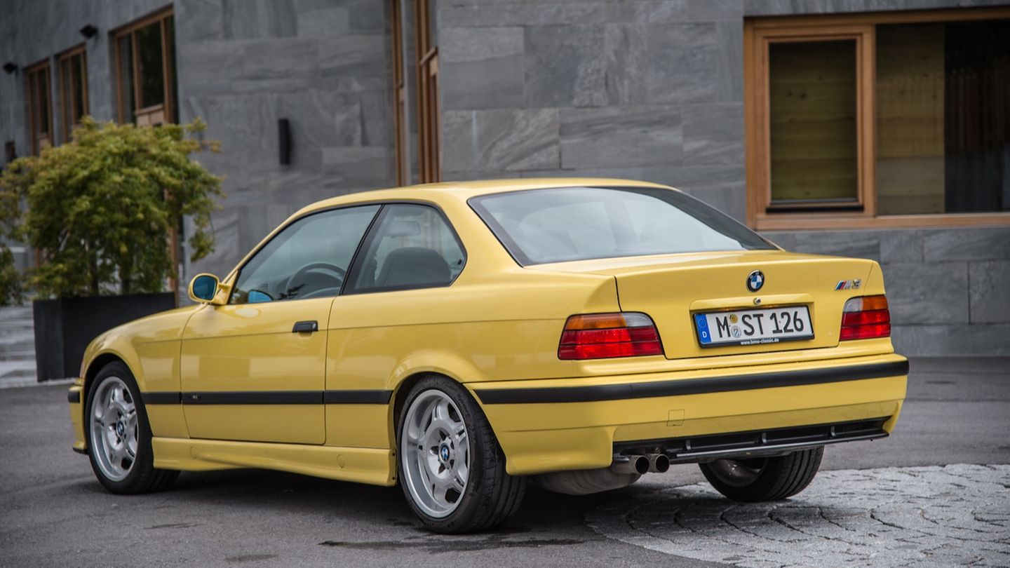 Ein knallgelber, länglicher BMW steht vor einer Hauswand aus grauem Stein