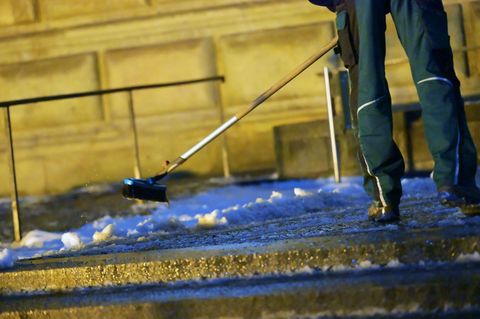 Ein Mann räumt Schnee vor der Alten Pinakothek in München. In der Nacht soll es wieder kälter werden, mit Schneefall bis in die