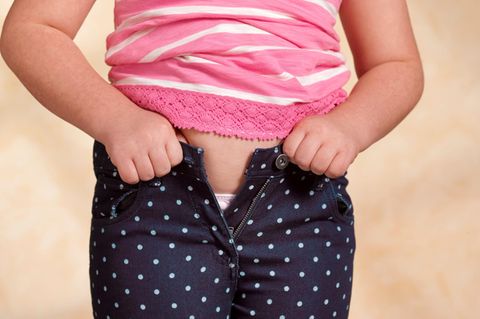 Ein Mädchen kann seine Hose nicht mehr zuknöpfen