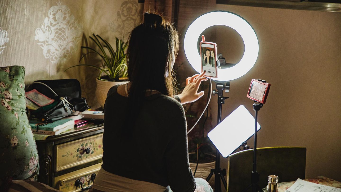 Influencer: eine Frau sitzt vor der Kamera und Ringlicht