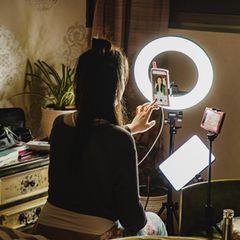 Influencer: eine Frau sitzt vor der Kamera und Ringlicht