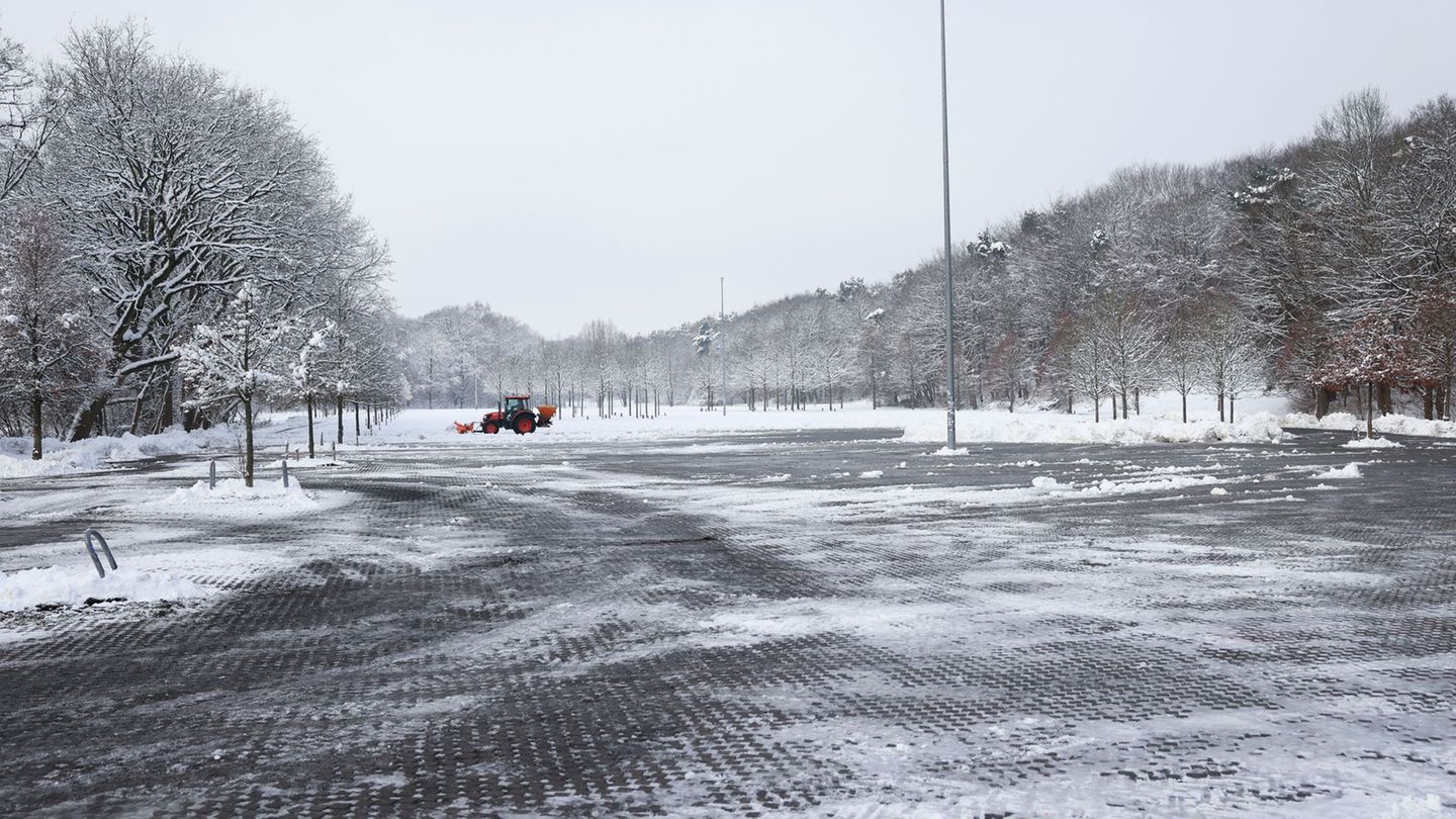 Ein Mitarbeiter befreit nahe der Barclays Arena einen Teil eines Parkplatzes vom Schnee. Foto: Christian Charisius/dpa