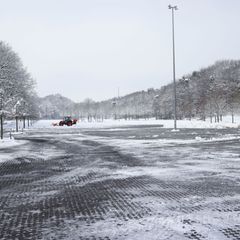 Ein Mitarbeiter befreit nahe der Barclays Arena einen Teil eines Parkplatzes vom Schnee. Foto: Christian Charisius/dpa