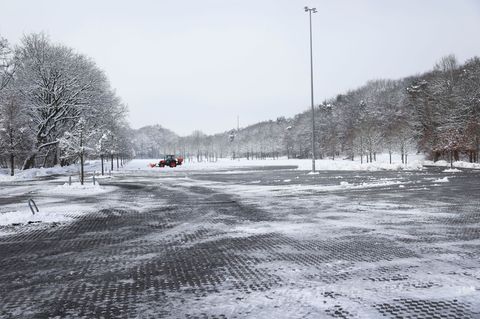 Ein Mitarbeiter befreit nahe der Barclays Arena einen Teil eines Parkplatzes vom Schnee. Foto: Christian Charisius/dpa