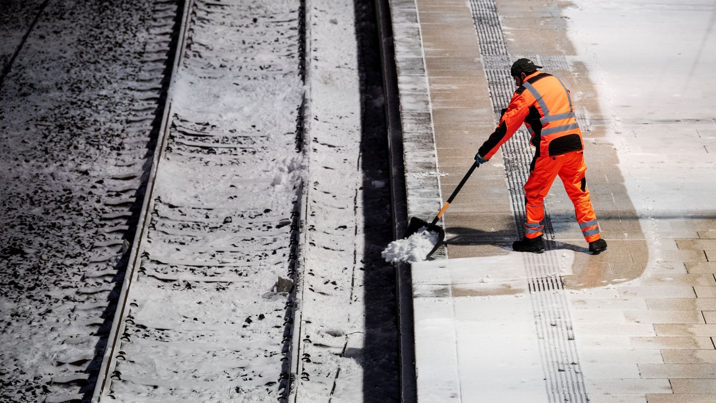 Ein Mann räumt am Morgen am Hauptbahnhof auf einem Bahnsteig am Hamburger Hapotbahnhof Schnee. Foto: Daniel Bockwoldt/dpa