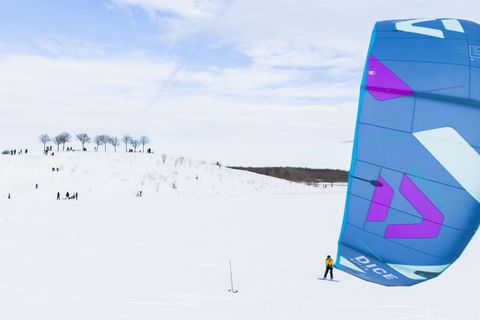 Ein Kite-Surfer gleitet am Kronsberg mit seinem Board über den Schnee. Foto: Julian Stratenschulte/dpa