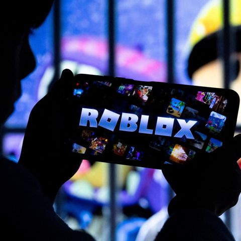 Ein Junge hält einen Bildschirm mit der Aufschrift "Roblox" in den Händen