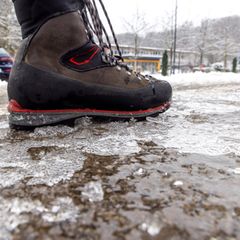 Eisregen in Hessen: Eine Person läuft über einen vereisten Gehweg