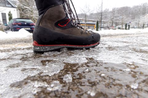 Eisregen in Hessen: Eine Person läuft über einen vereisten Gehweg
