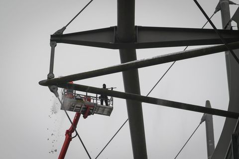 Arbeiter mit einem Hubsteiger entfernen Eis und Schnee von den Trägern des Stadiondachs am Volksparkstadion. Foto: Christian Cha