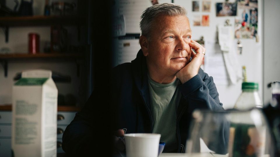 Midlife Crisis: Ein Mann sitzt am Küchentisch und denkt nach