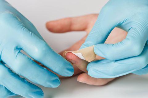 Entzündungen Arzt versorgt Wunde am Finger mit Pflaster