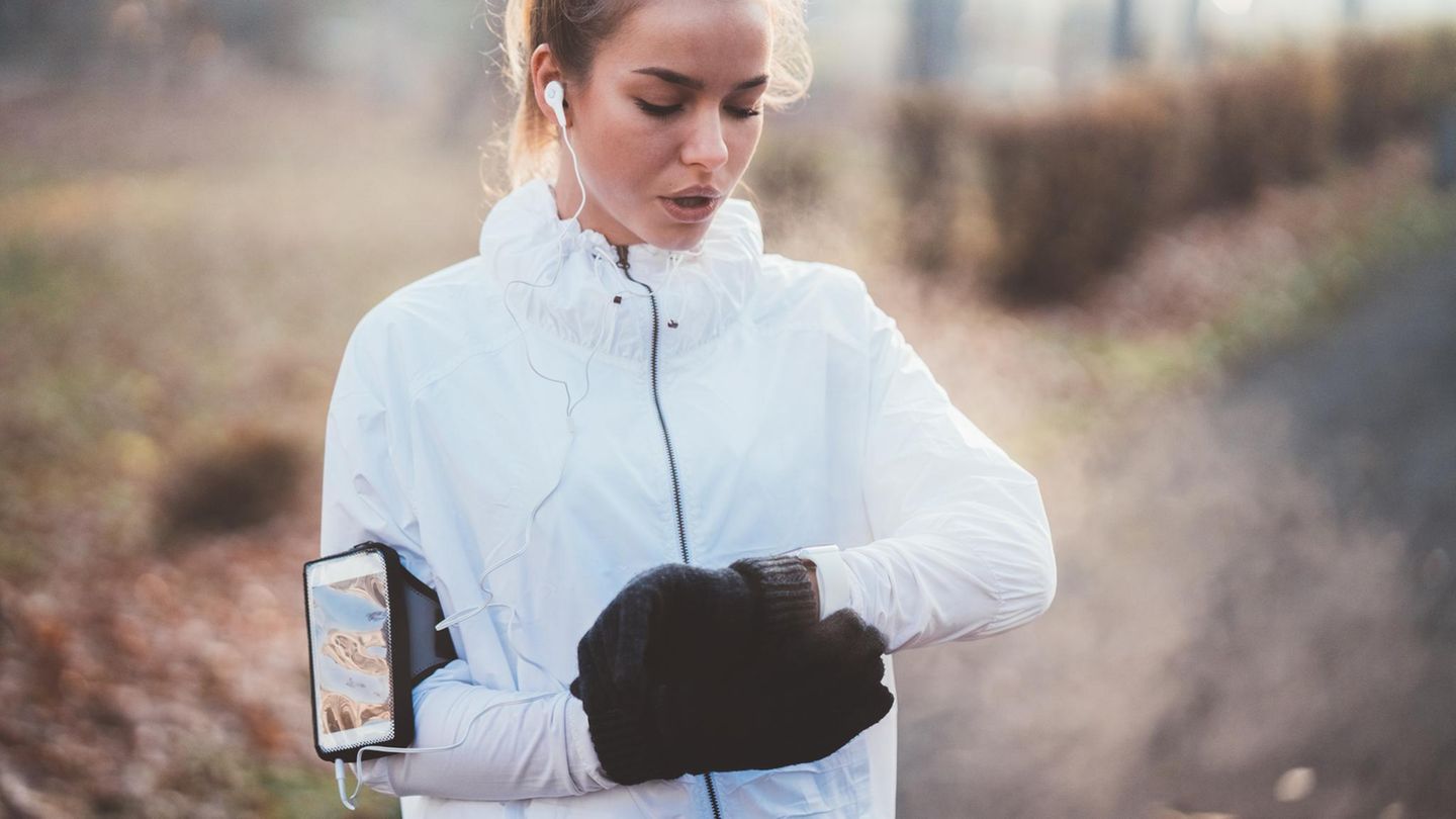 Fitness: Frau beim Joggen blickt auf ihren Fitnesstracker