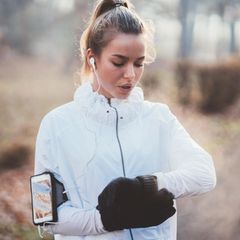Fitness: Frau beim Joggen blickt auf ihren Fitnesstracker