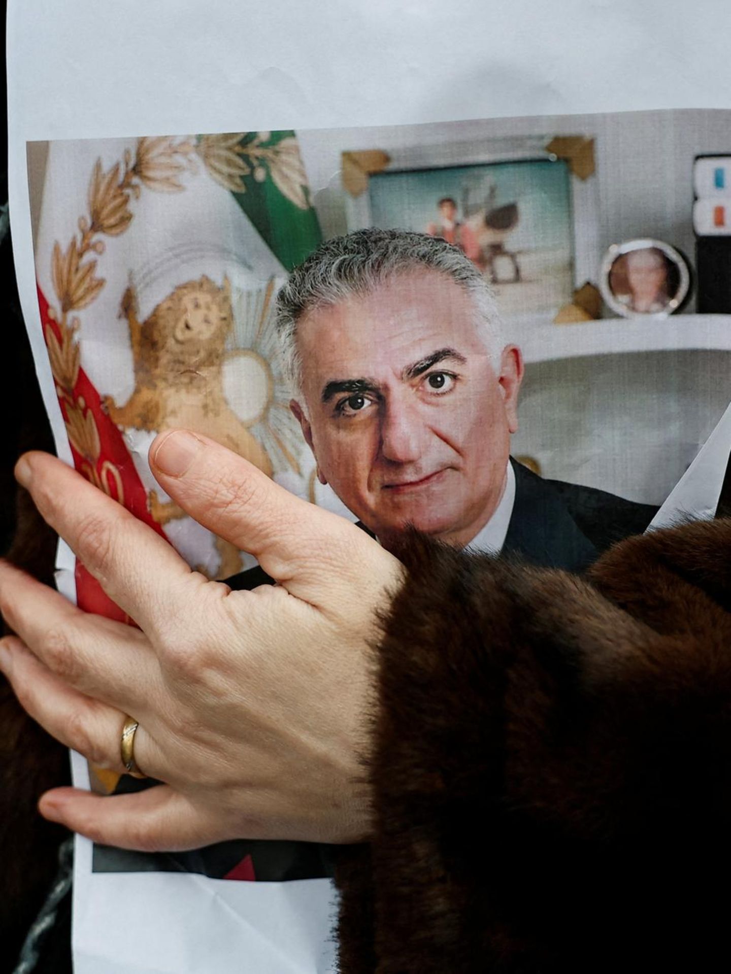 Eine Frau hält ein Bild von Reza Pahlavi im Arm